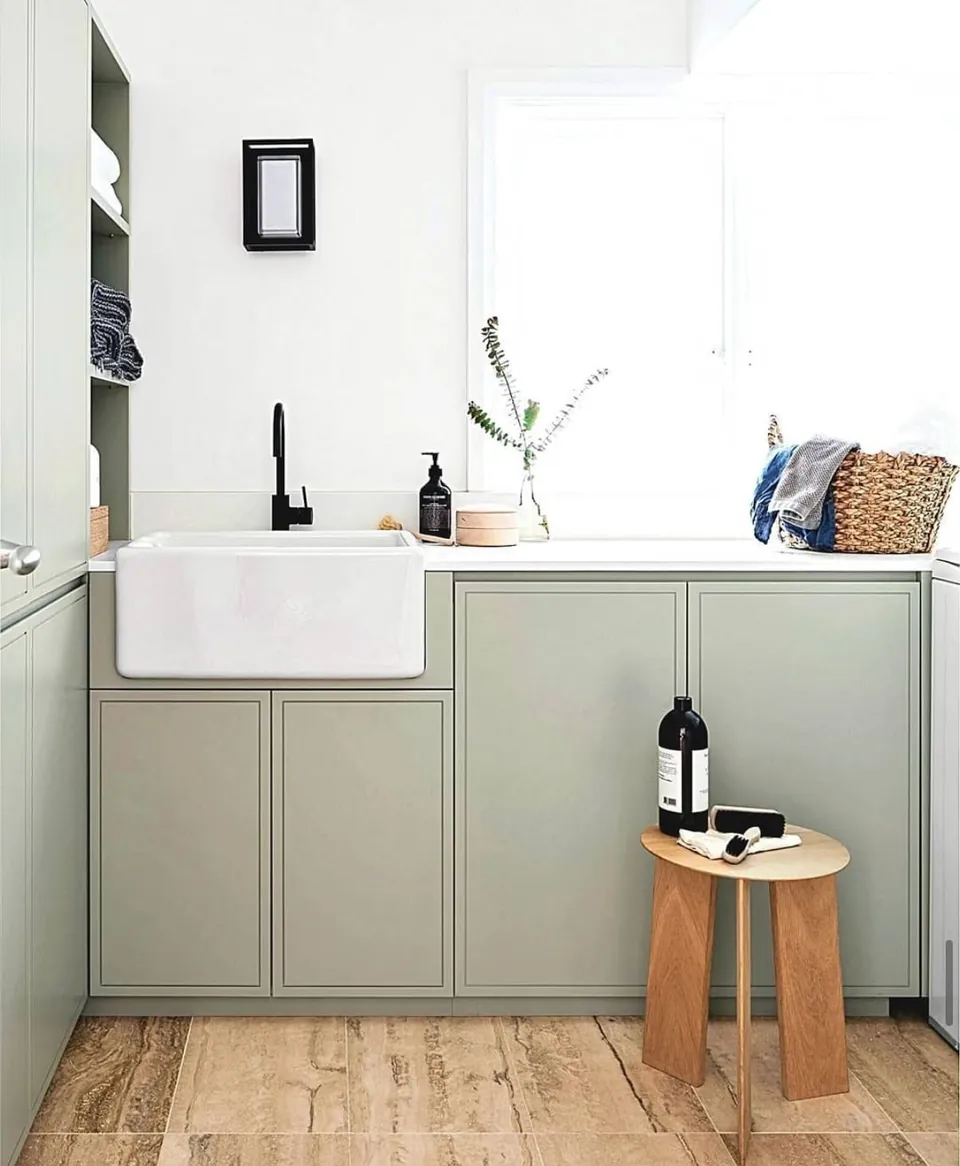 Cocina con muebles verde salvia, fregadero cerámico y suelo de madera