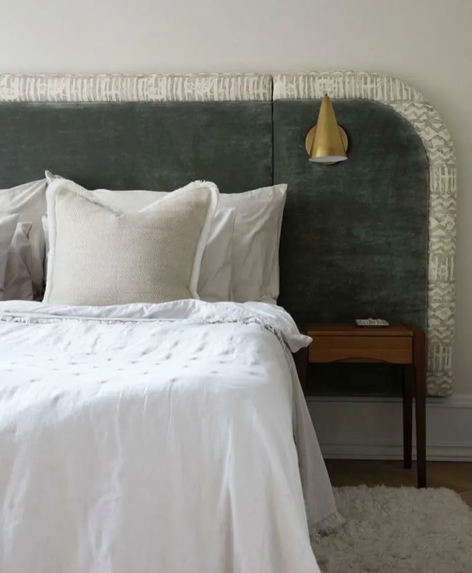 Dormitorio con cabecero curvo de terciopelo verde y ropa de cama blanca