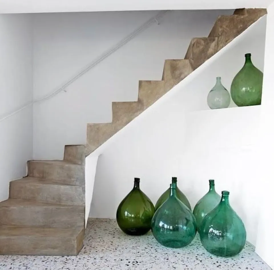Escalera de obra con nicho y damajuanas de vidrio verde