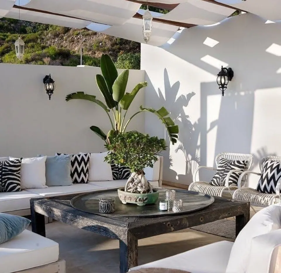 Terraza chill out con toldos, sofás blancos y mesa de madera envejecida