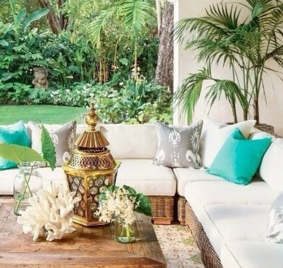 Terraza con sofá blanco, cojines turquesa y jardín tropical